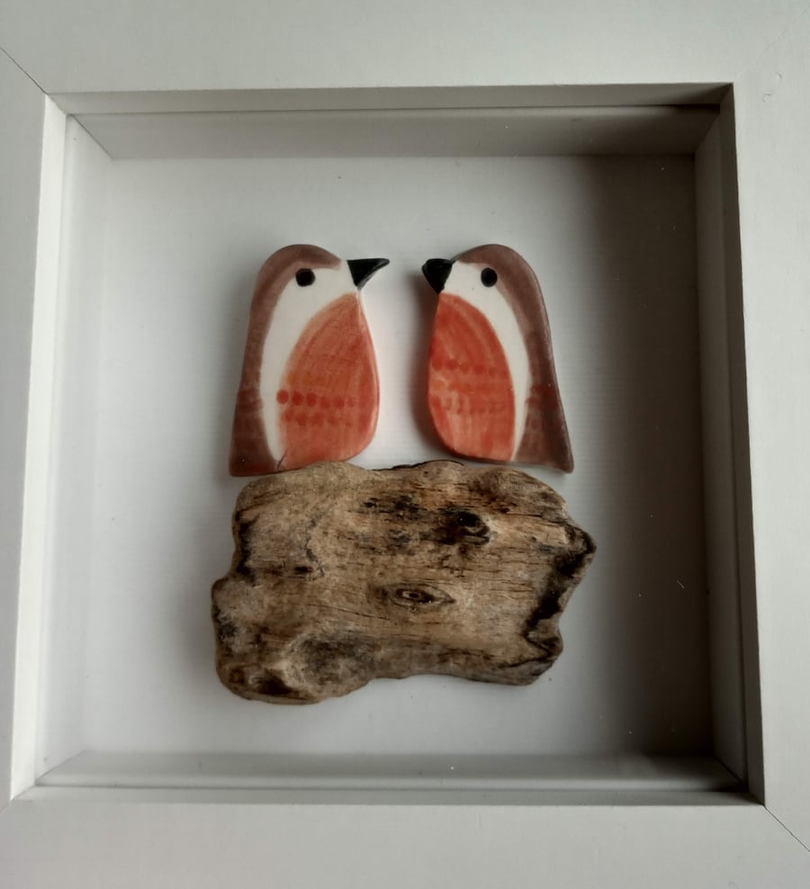 Cute ceramic robins perched on driftwood in a frame
