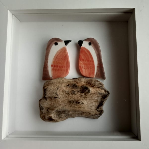 Cute ceramic robins perched on driftwood in a frame