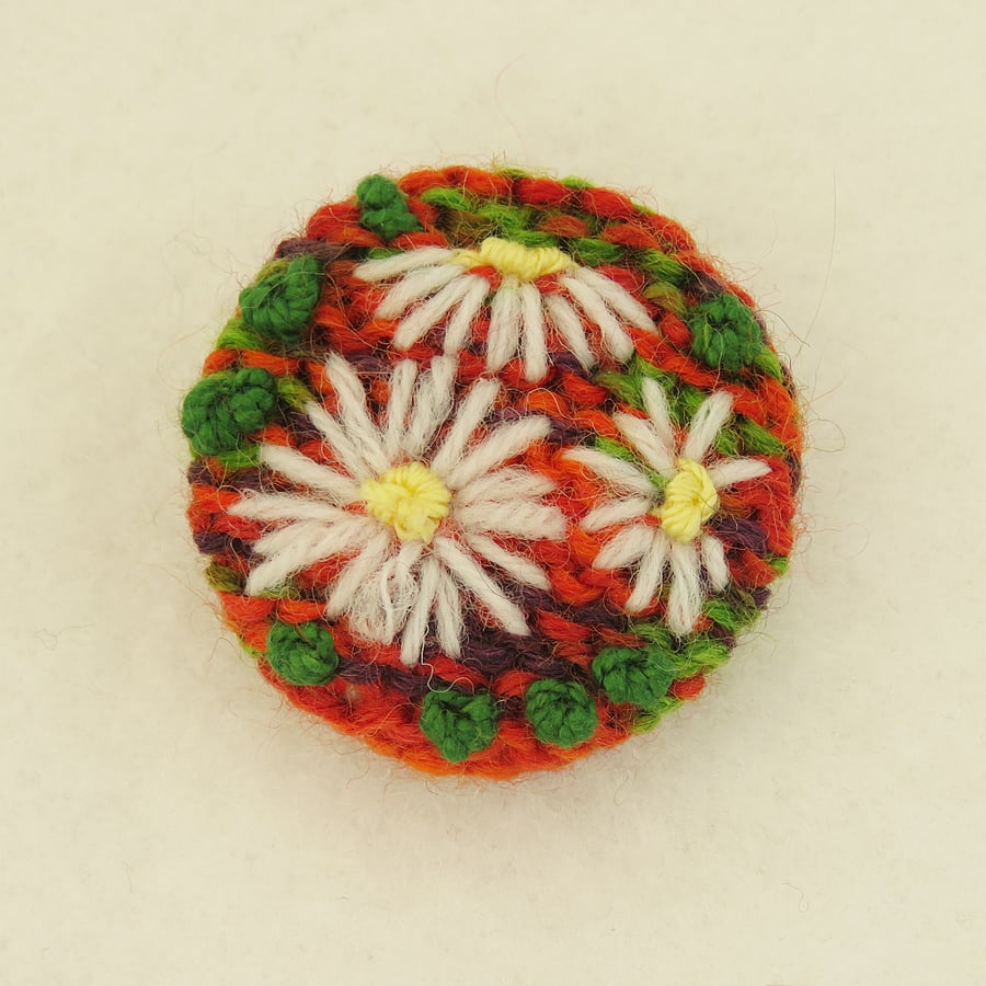 Daisy Brooch embroidered on knitted red, green and purple background
