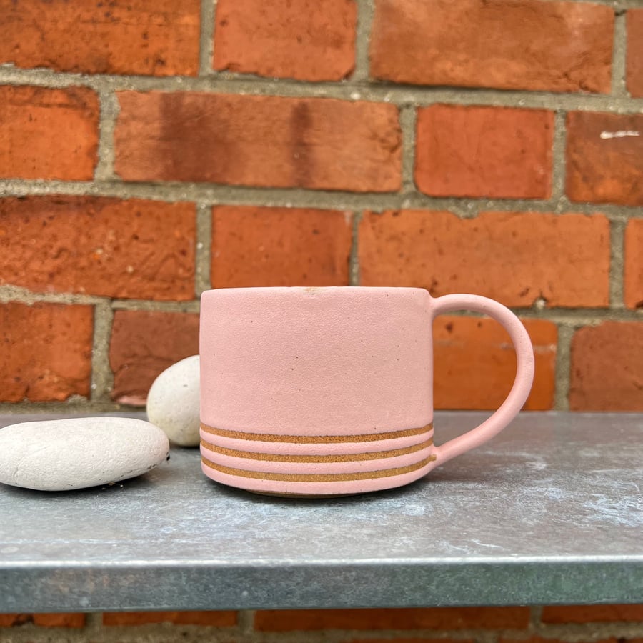 Hand made pink pottery mug with tape resist detail. 