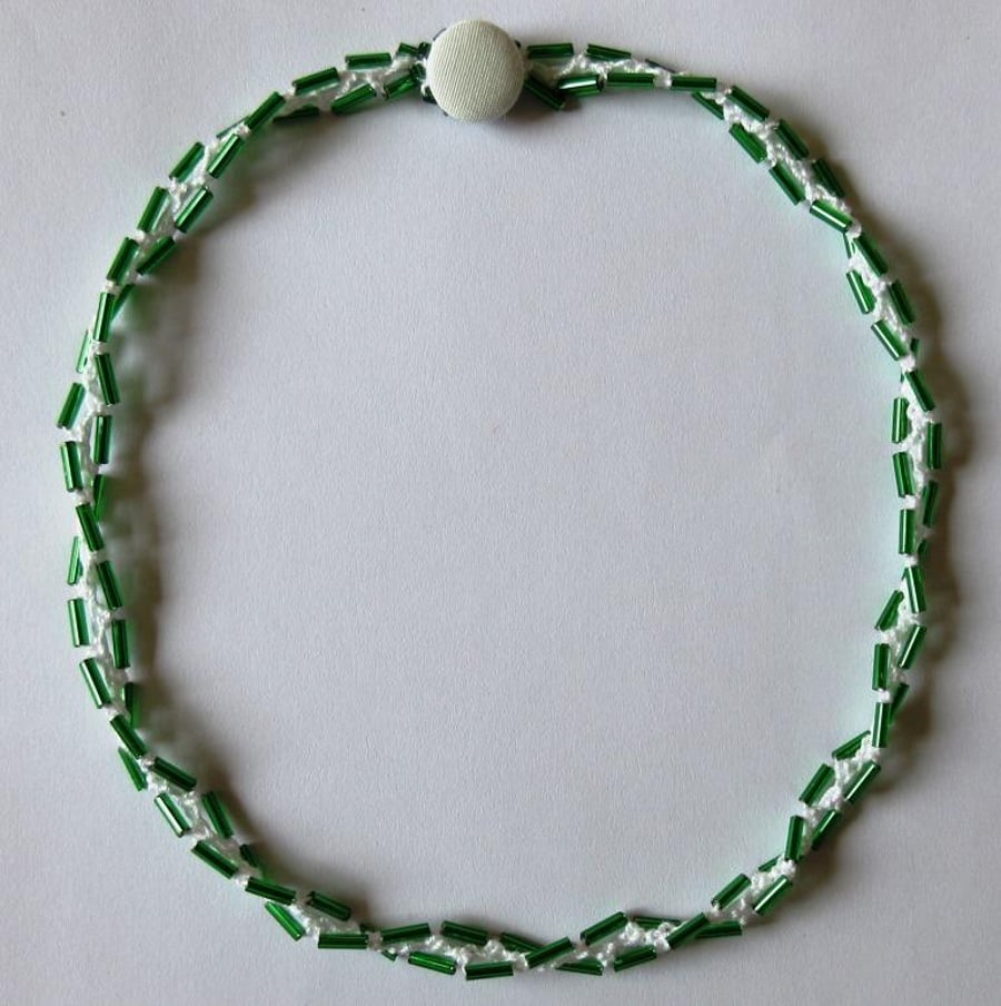 A crocheted necklace in white cotton with green bugle beads