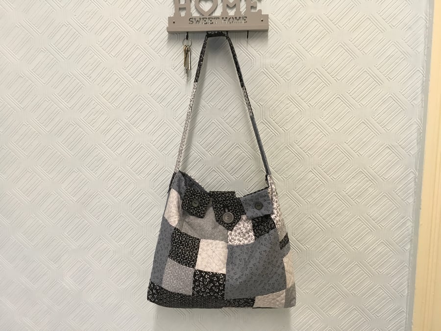 A Softly Quilted Patchwork Bag in Black, Grey and White, with a Shoulder Strap.