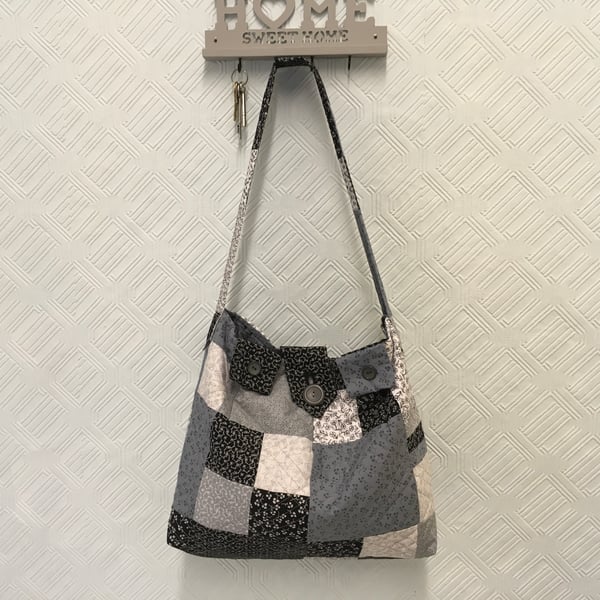 A Softly Quilted Patchwork Bag in Black, Grey and White, with a Shoulder Strap.