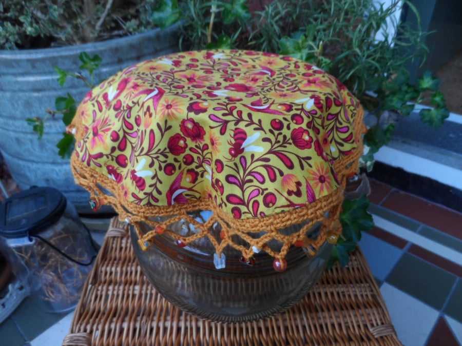 Insect Jug Cover in a deep pink and mustard bee and floral print fabric. 