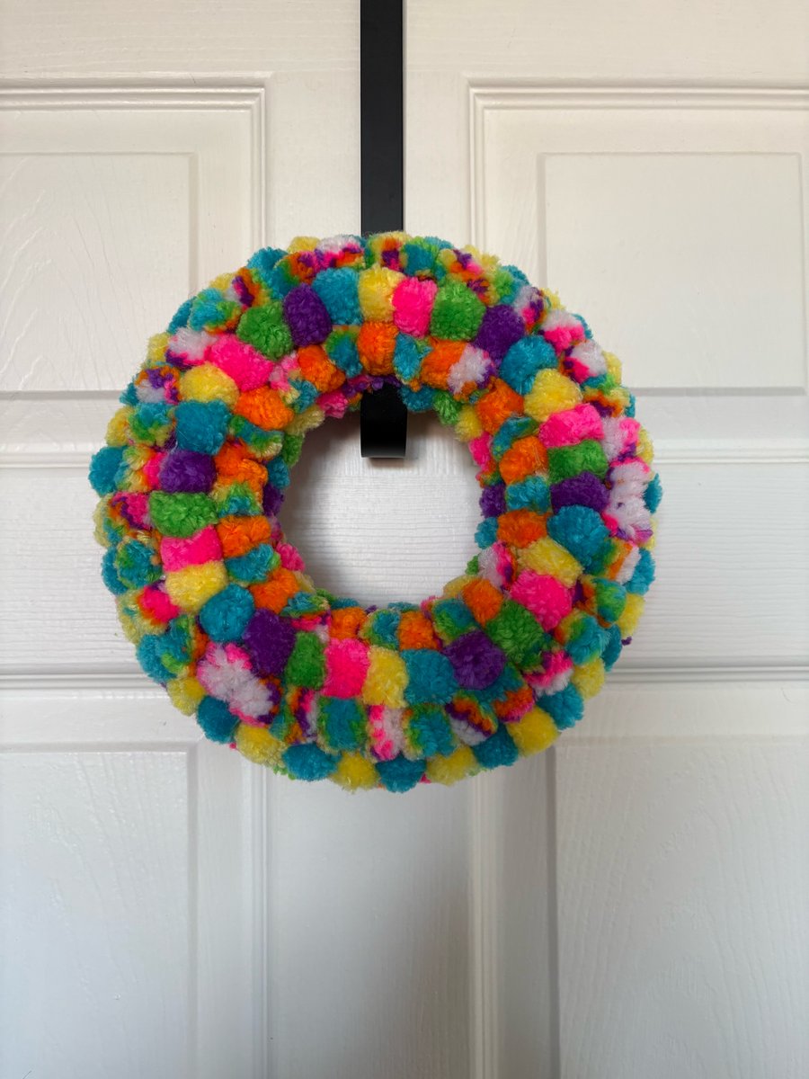 Pom pom decorated rainbow wreath. 