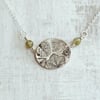Botanical silver pendant with leaf design.