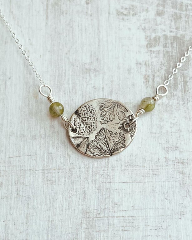 Botanical silver pendant with leaf design.