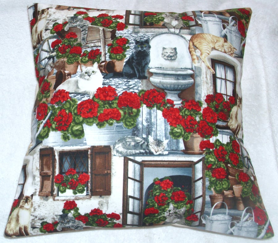  Cats and bright red Geraniums on the patio cushion