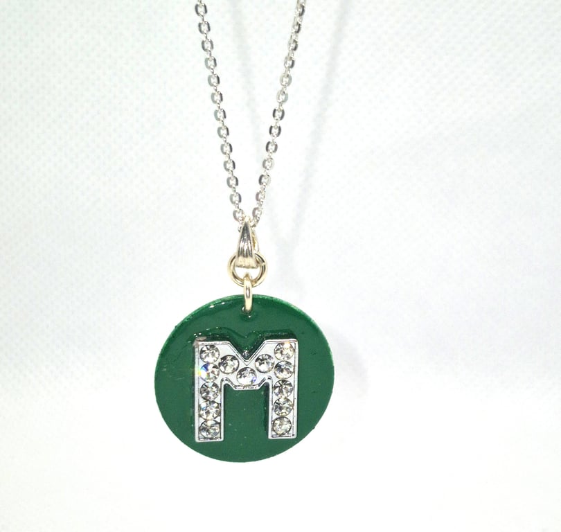 Green enamel disc pendant with faux crystal letter "M" attached