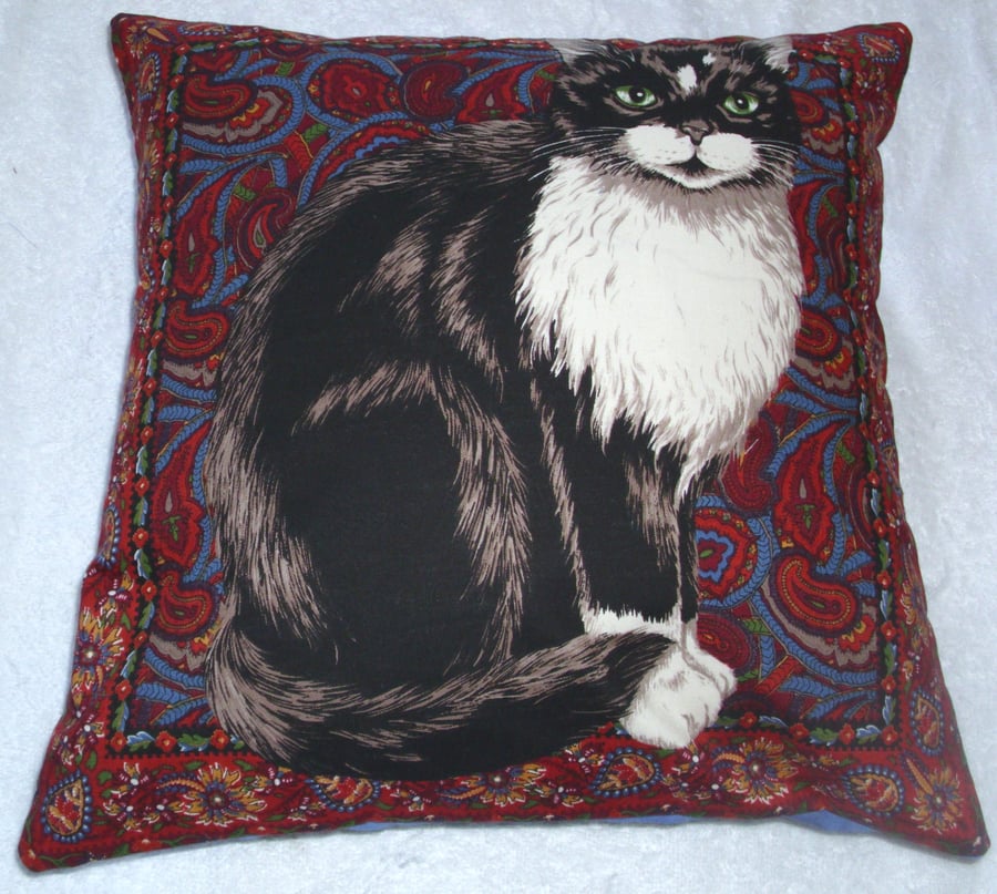 Tapestry cat cushion with a black and white cat sitting waiting patiently