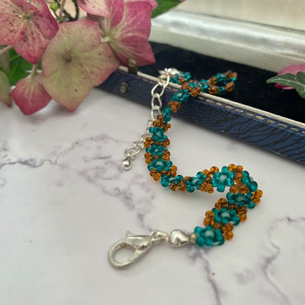 Delicate seed bead daisy chain bracelet in bright teal and burnt orange colours.
