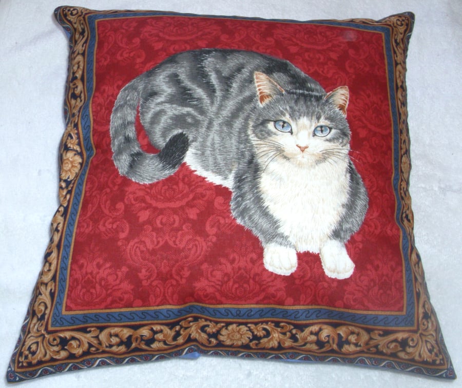 A very pretty grey and white cat lying on a red background cushion