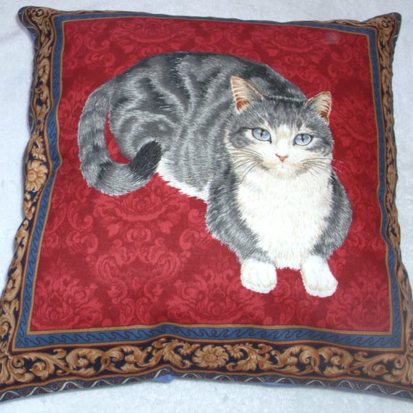 A very pretty grey and white cat lying on a red background cushion