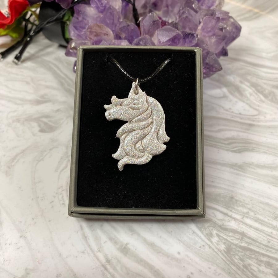 White unicorn sparkly polymer clay necklace on black cord chain.