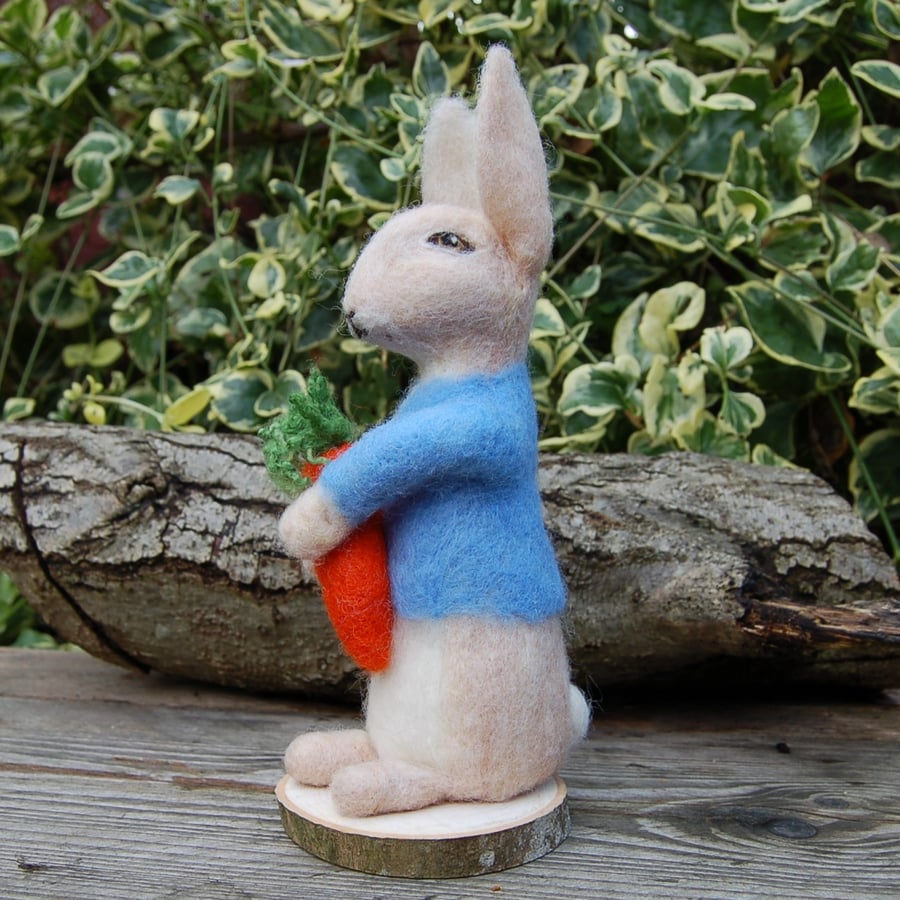 Needle felt rabbit in blue jacket holding a carrot