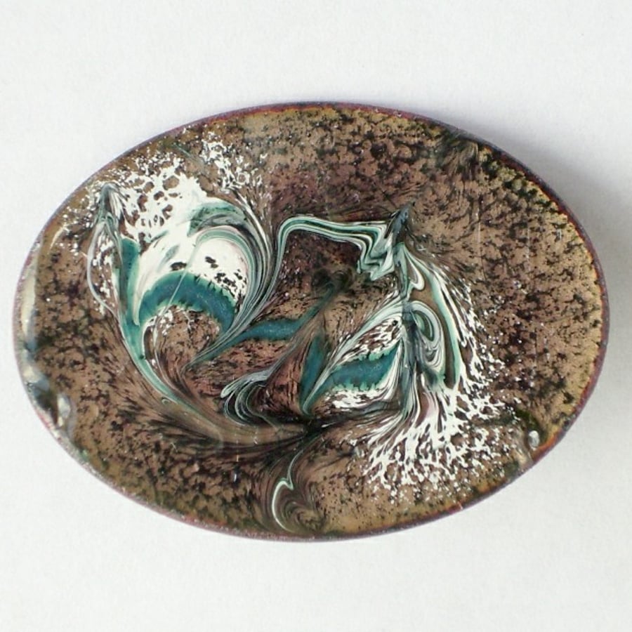enamel brooch - oval: scrolled white and dark green on black over clear