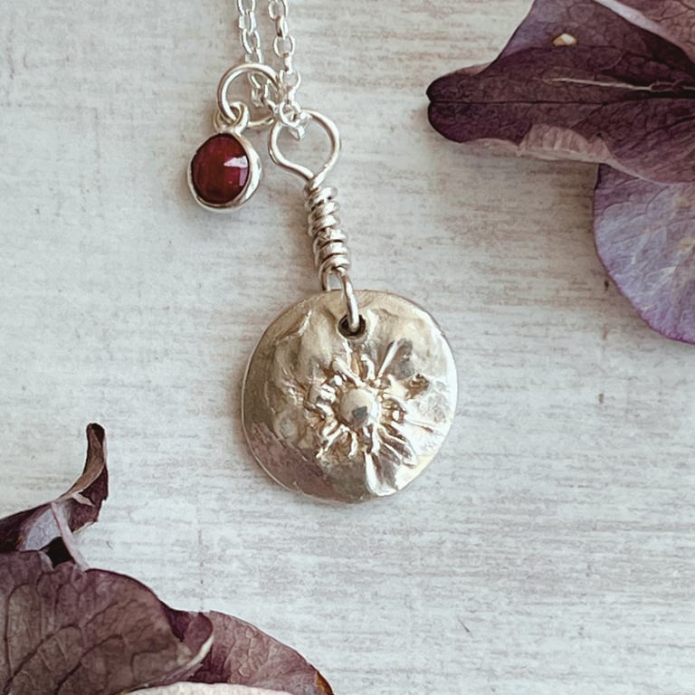 Botanical silver pendant with strawberry flower and a ruby charm.