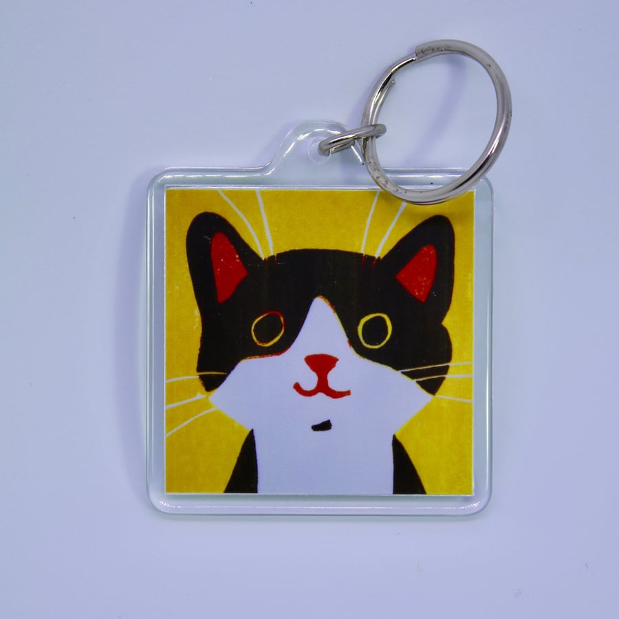 LITTLE BLACK AND WHITE HAPPY CAT KEYRING WITH YELLOW BACKGROUND