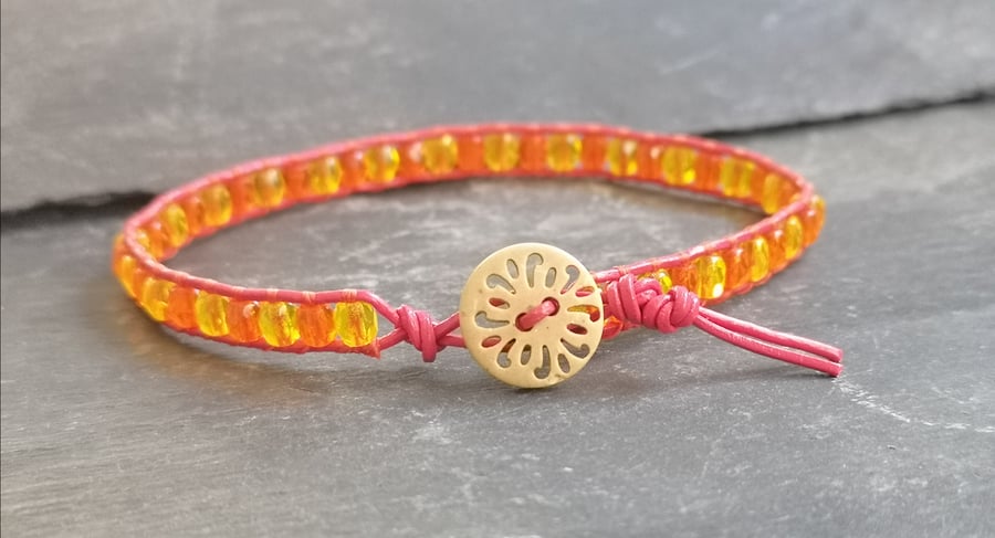 Pink leather bracelet with orange and yellow beads and wooden button fastener