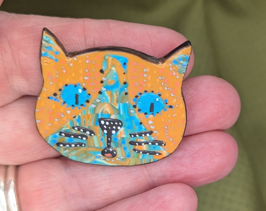 The happy cat brooch with orange and blue colouring.
