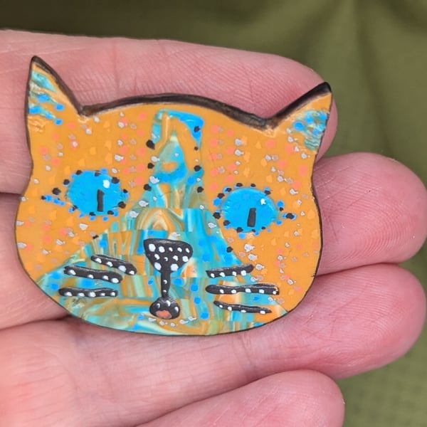 The happy cat brooch with orange and blue colouring.
