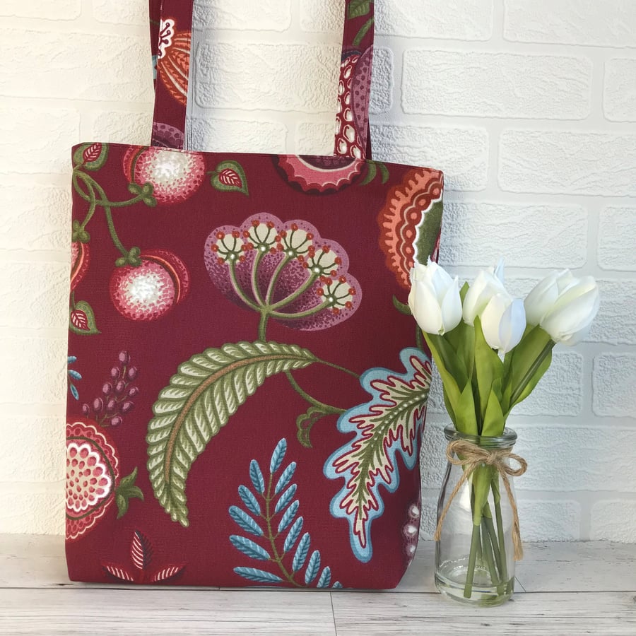 Burgundy tote bag with stylised floral seed head, fruit and foliage print