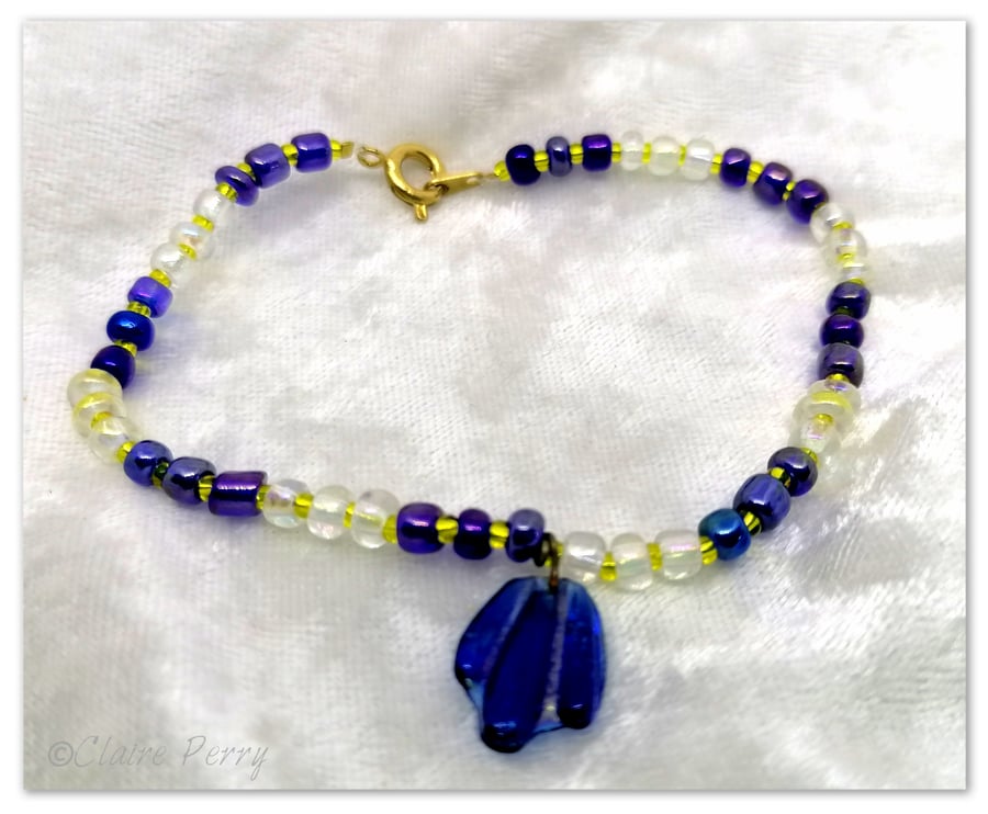 Seed bead bracelet with blue and gold glass beads with a blue glass charm.