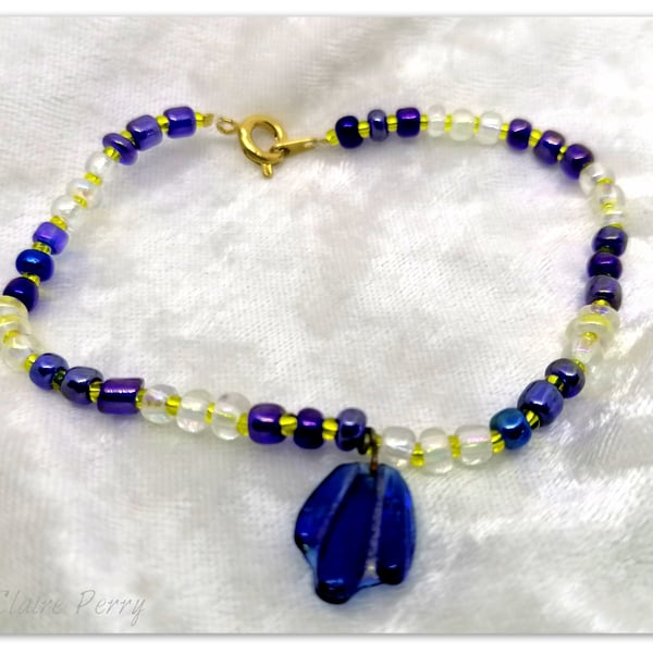 Seed bead bracelet with blue and gold glass beads with a blue glass charm.