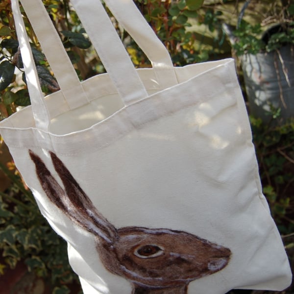 A needle felted hare portrait on a Canvas tote bag.