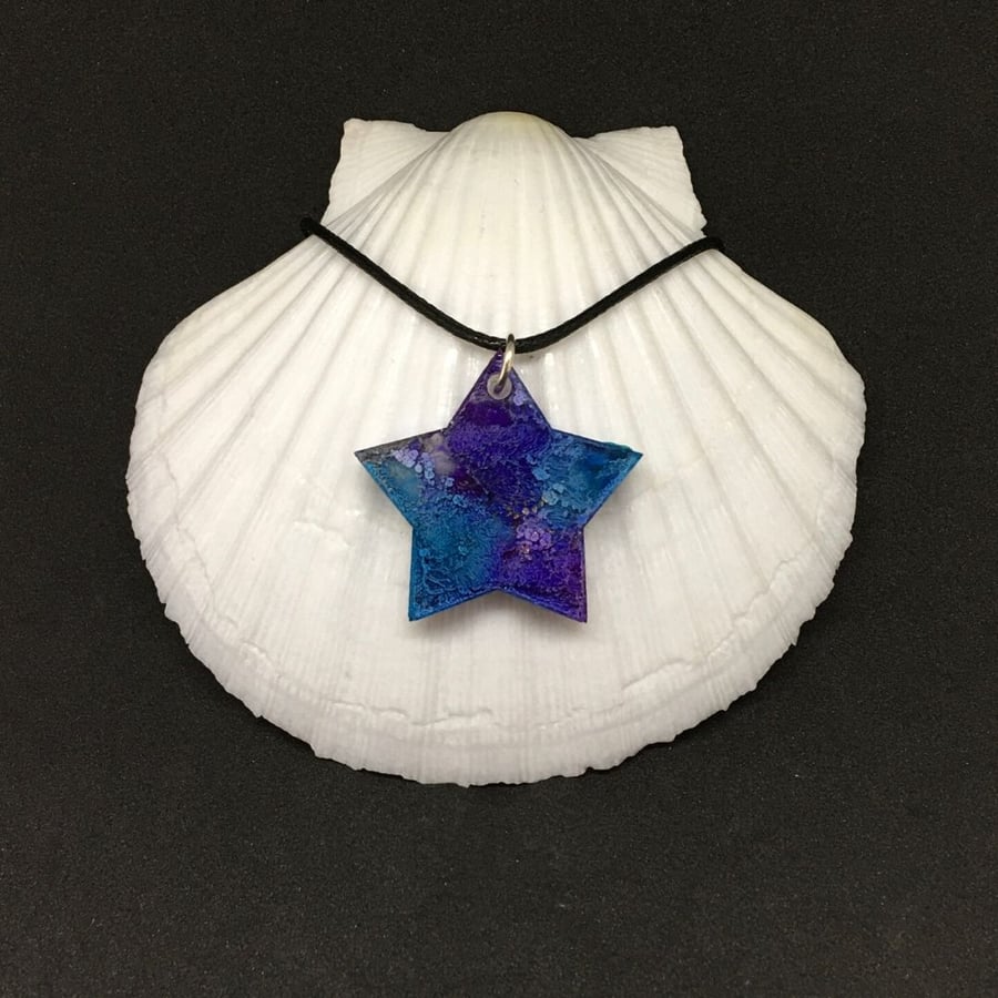 Star blue and violet resin and ink pendant with black cord.
