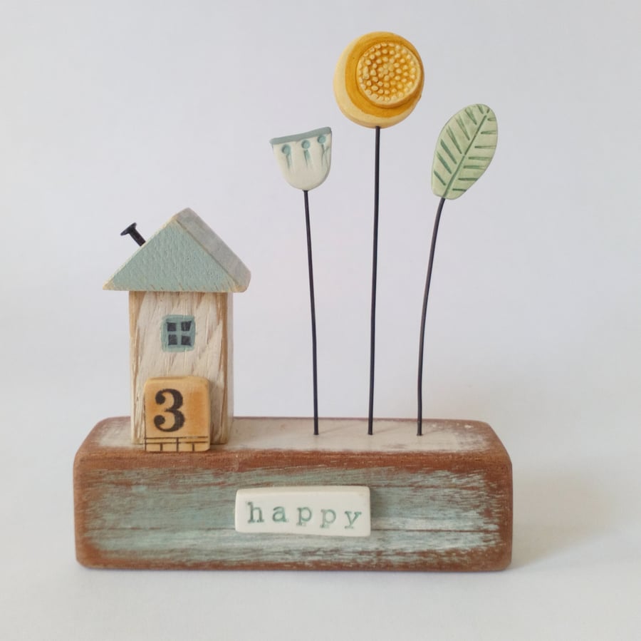 Little wooden house with clay flower garden 'happy'