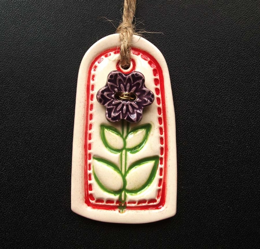 Small red ceramic tag decoration with flower button