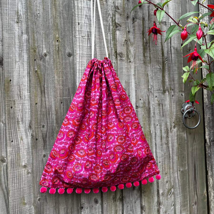 Bright pink, purple and orange floral cotton drawstring bag with pompoms unlined