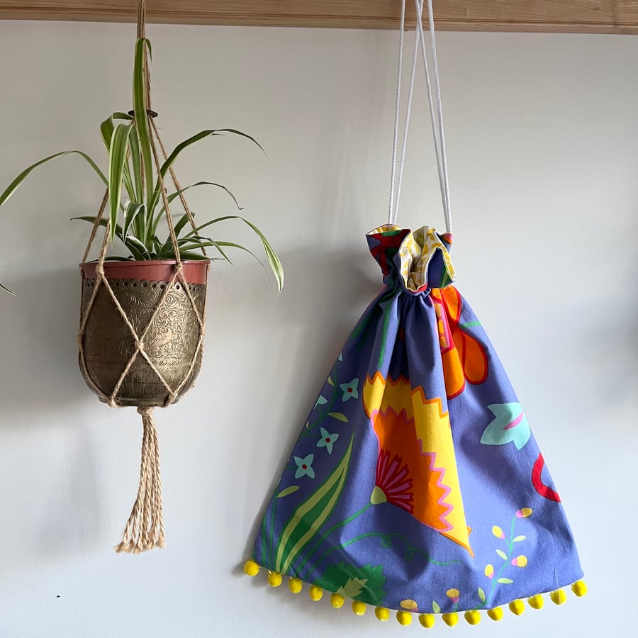 Bright purple floral cotton drawstring bag with pompoms