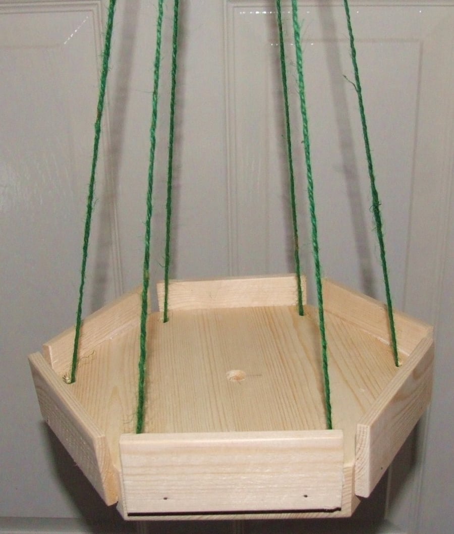 Little wooden hexagonal hanging bird table on twine for wild or garden birds.