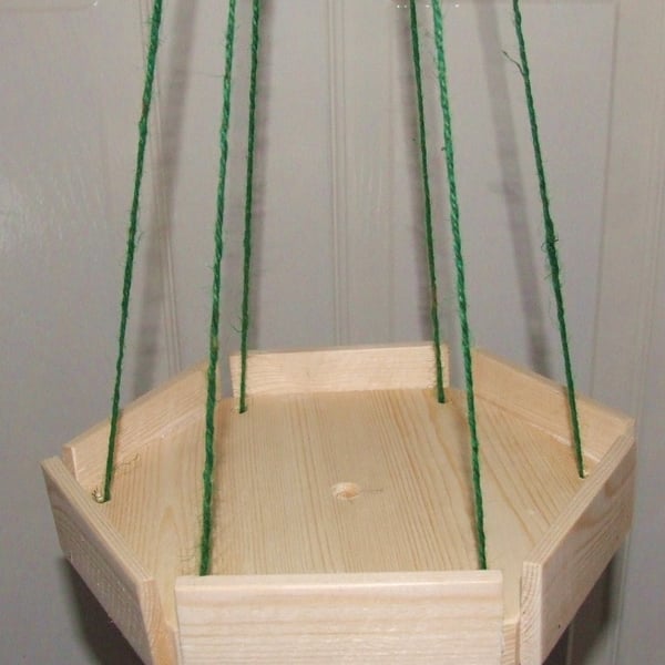 Little wooden hexagonal hanging bird table on twine for wild or garden birds.