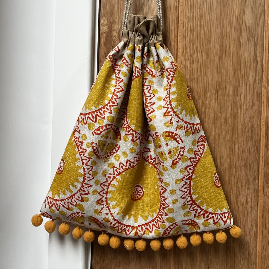 Ochre print linen drawstring bag with pompoms and linen lining