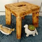 Rustic burnt wooden stool with cutout handle. Farmhouse decor.