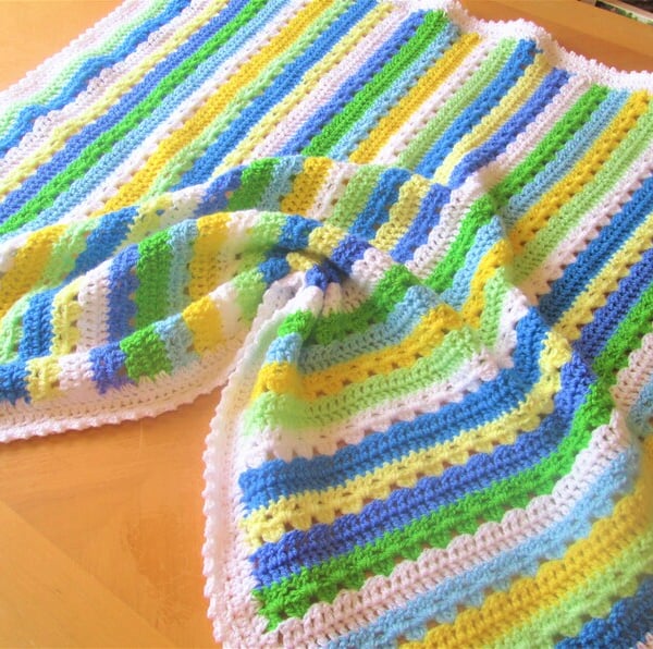 Handmade crochet baby or toddler blanket in white, blue, green and yellow 