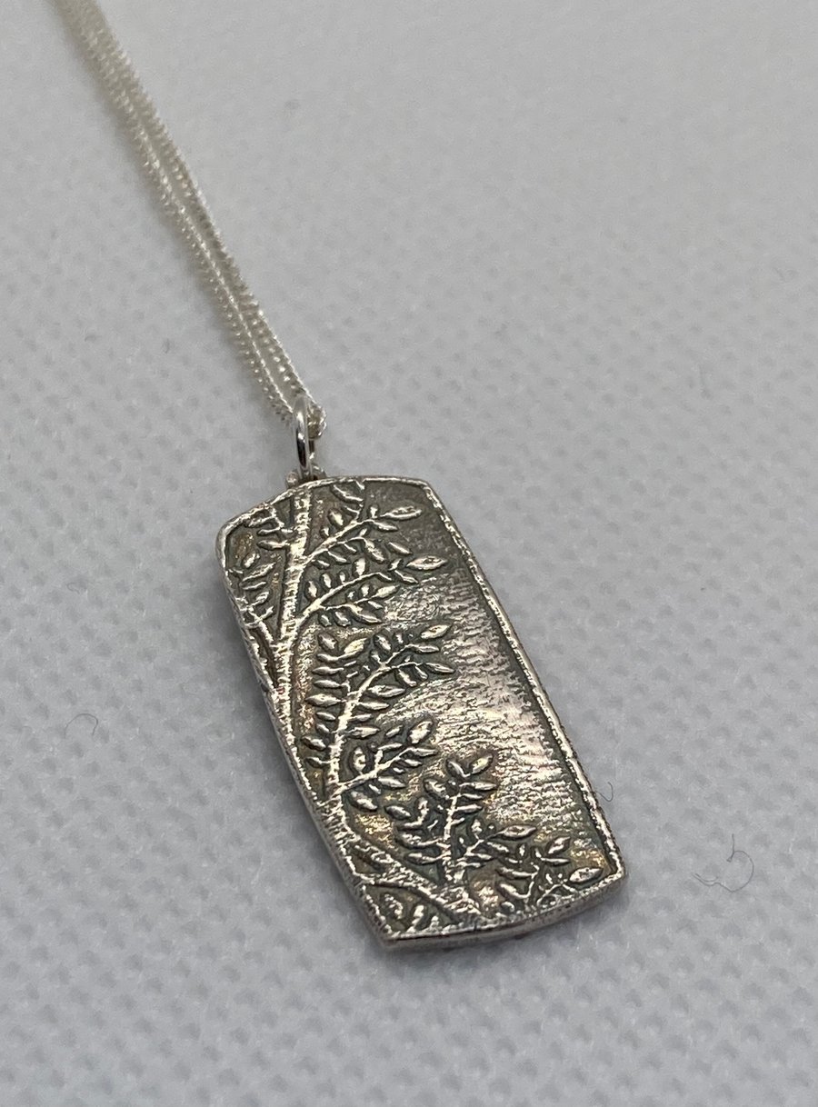 Silver pendant with delicate leaves pattern. 