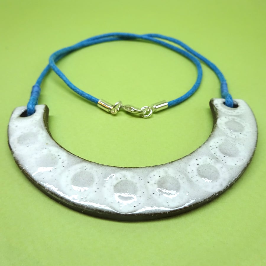 Ceramic arc bib necklace on a teal blue cord