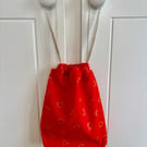 Red cotton drawstring bag with red and orange hearts, with linen style ribbon.