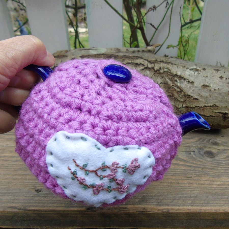 crochet tea cosy with hand embroidered blossom on a felt heart 