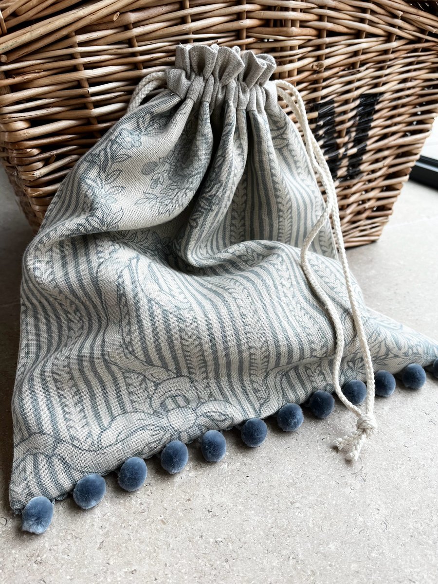 Pale blue print linen drawstring bag with pompoms and linen lining