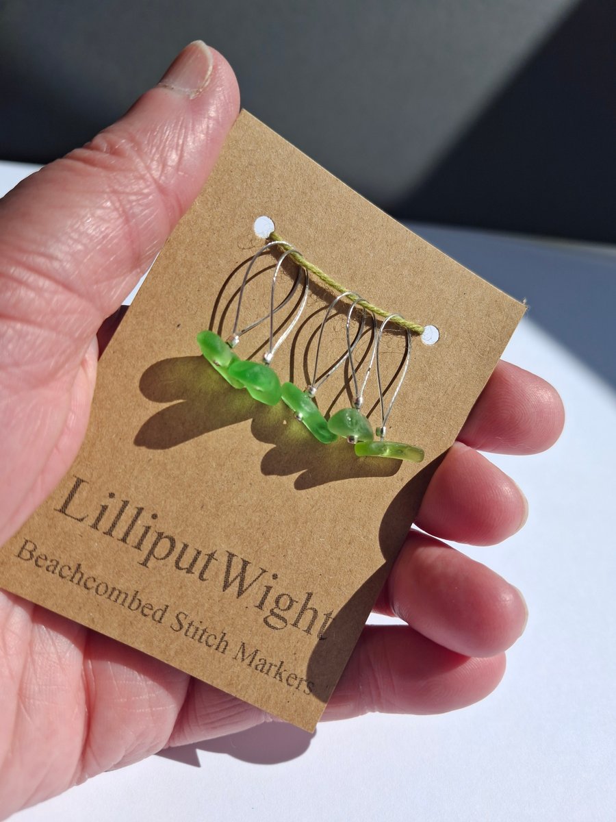 Five sea glass stitch markers in shades of green
