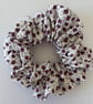Cotton scrunchie hair accessory in a floral print in white and purple.