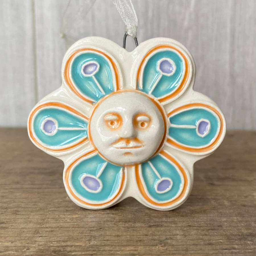 Intricate ceramic flower decoration with face blue orange