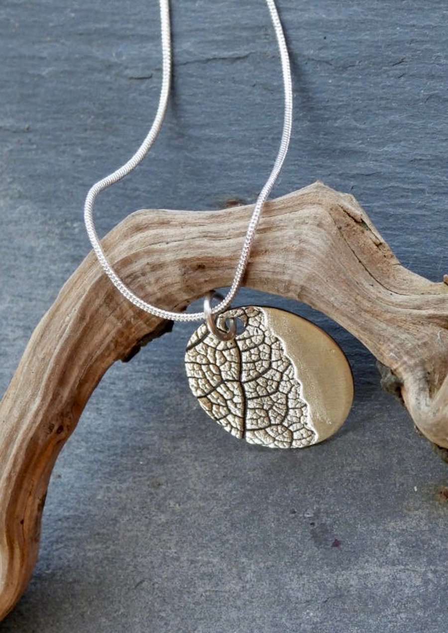 Round Pendent Necklace With An Imprint Of A Leaf.