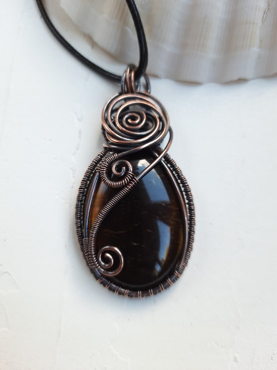 Pendant with tiger'sPendant made of copper wire and tiger's eye.  eye. 