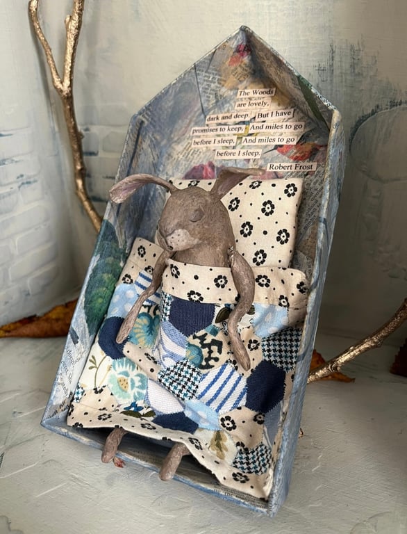 Paper mache sleeping hare under handmade quilt